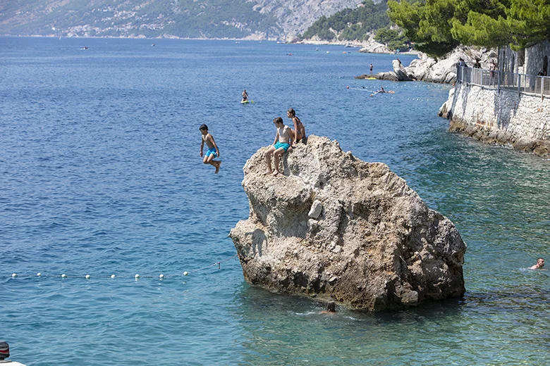 children jumping in the sea in Brela, Croatia